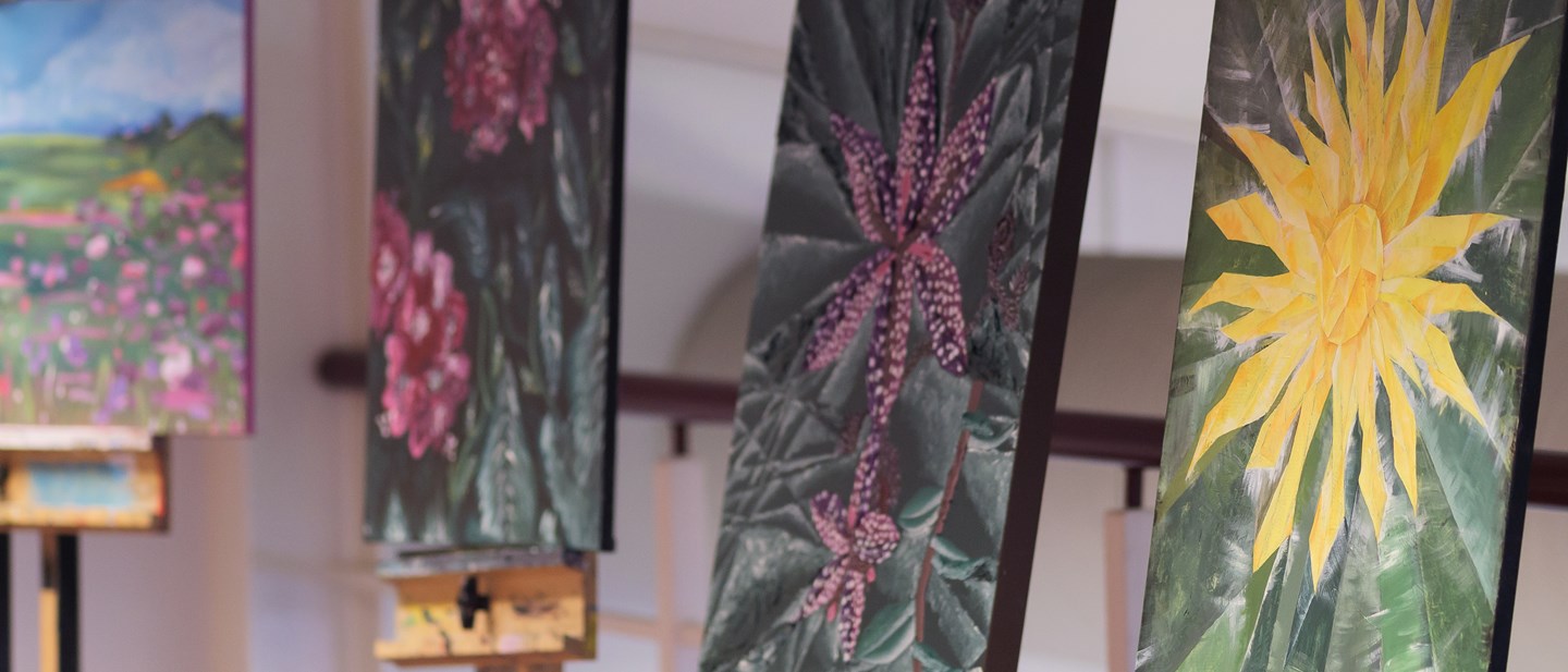 Art students work displayed - three separate paintings of flowers