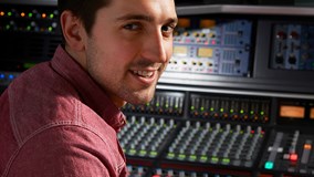 Male sitting in a recording studio mixing tracks