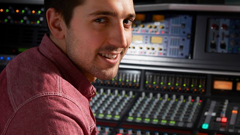 Male sitting in a recording studio mixing tracks