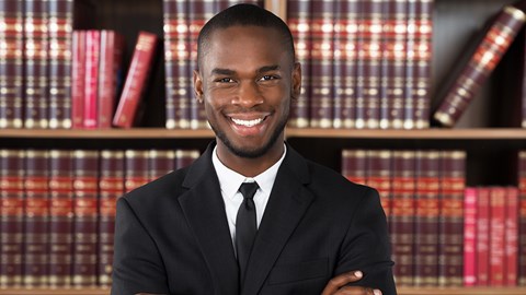 Young male lawyer standing in front of book case