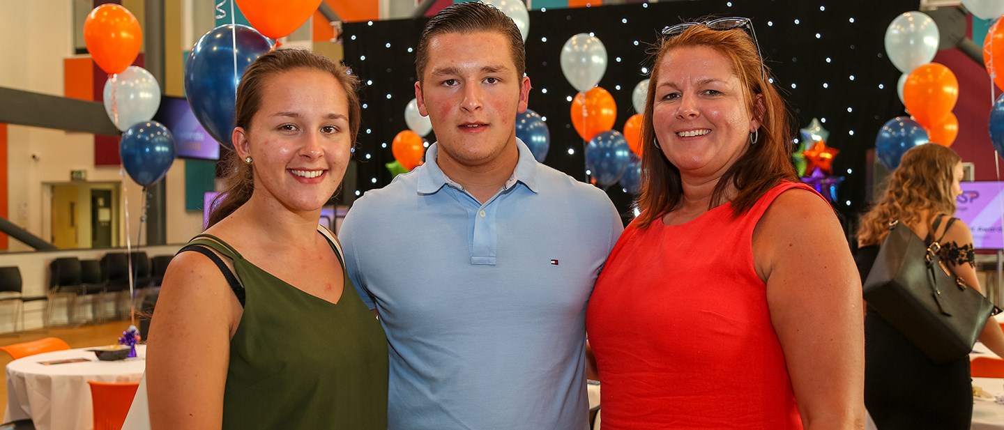 Male student with sister and mum either side at student awards