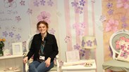 Professional (vocational) student sitting in a interior design set she created, including a chair, hand designed wallpaper and a table