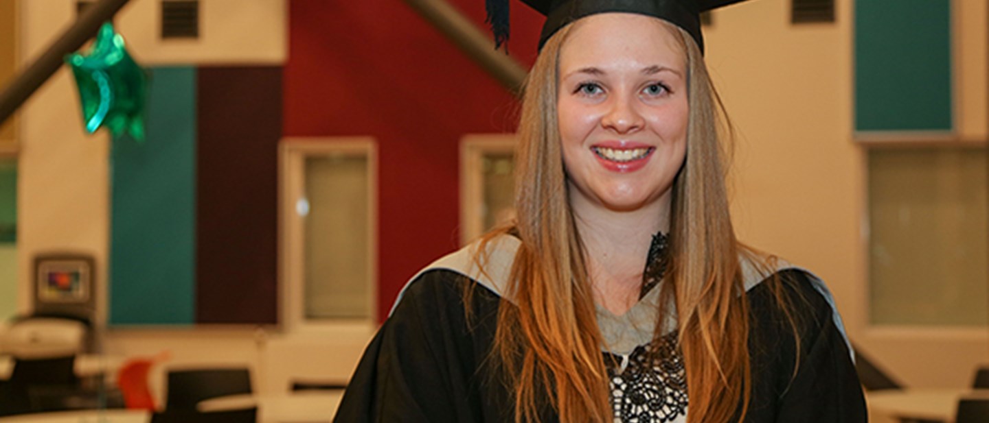 Higher Education student Holly Archer at Graduation wearing robe and hat