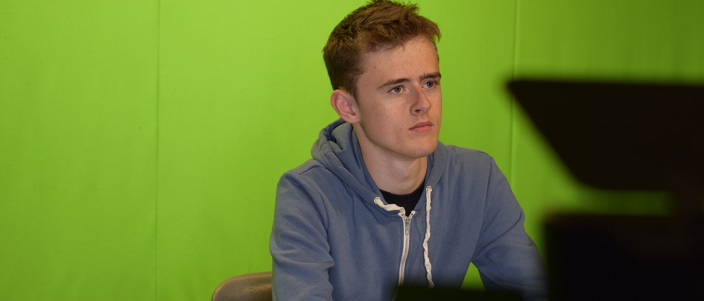 Male student in the Green Screen Room surrounded by stage lighting