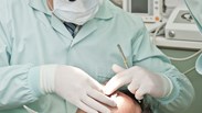 Dentist working wearing white glove with a tool in their hand