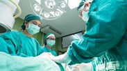 three doctors in a theatre conducting surgery 