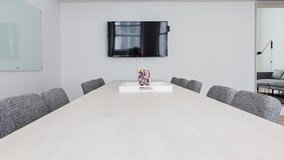 Empty board room with a white table, black chairs and a TV screen