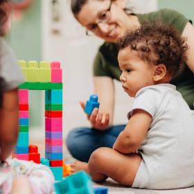 A young Student with a baby showing her a blue blocks.