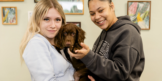 Two students holding a puppy.
