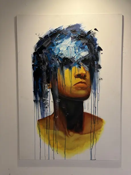 A photograph of an abstract hand painting. The painting is of a boy with much of his face obscured by blue abstract strokes.
