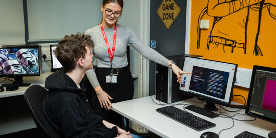 Staff teaching a student on a computer.