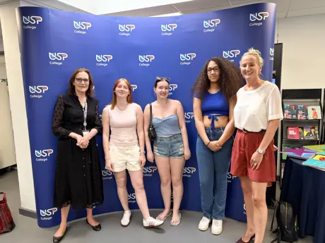 Two women and three female students smiling at the camera