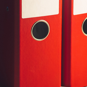 Red binder folders on a shelf.