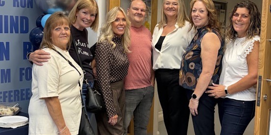 group picture of 7 people (6 women with 1 man in the middle) all smiling looking into the camera